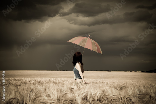 Photo: Girl with umbrella at field in retro style Girl with umbrella at field in retro style