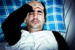 Very stressed man with a headache laying in bed