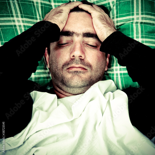 Photo: Stressed or mentally disturbed man laying in bed Stressed or mentally disturbed man laying in bed