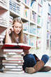 Smiling young adult woman reading  book in library