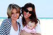 two beautiful girls with a baby on the beach