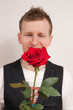 junger Mann haelt rote Rose in Hand
