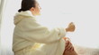 Young attractive woman in bathrobe drinking tea by the window