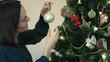 Woman decorating Christmas tree, close up
