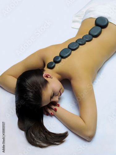 Foto: Model in a massage studio with hot stones on the back Model in a massage studio with hot stones on the back