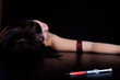Drug addict woman with syringe is sleeping on table