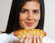 Joven mujer comiendo un hotdog.