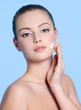 Young woman applying cream on face