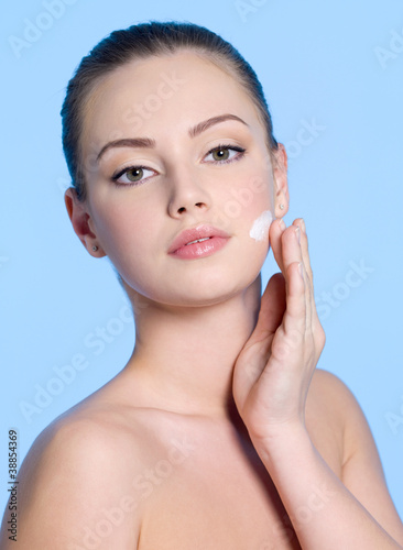 Photo: Young woman applying cream on face Young woman applying cream on face