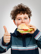 Boy eating big sandwich showing OK sign