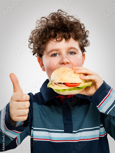 Photo: Boy eating big sandwich showing OK sign Boy eating big sandwich showing OK sign