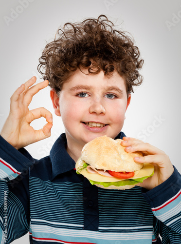 Photo: Boy eating big sandwich showing OK sign Boy eating big sandwich showing OK sign