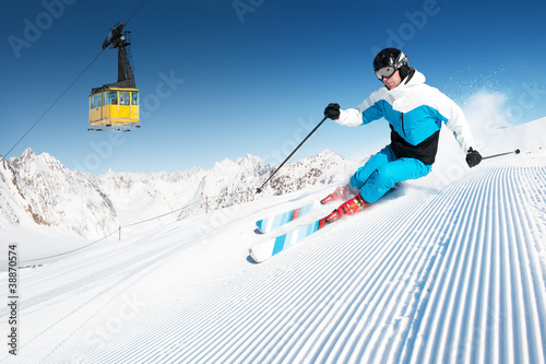 Photo: Skier in mountains, prepared piste and sunny day Skier in mountains, prepared piste and sunny day