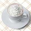 Tasse Kakao mit Sahnehäubchen auf Karodecke