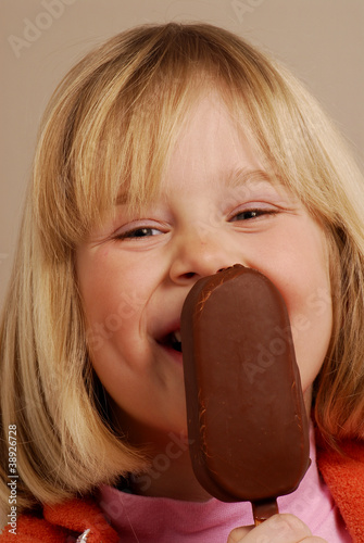 Foto: Niña comiendo una paleta de helado de chocolate. Niña comiendo una paleta de helado de chocolate.