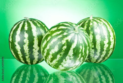 Photo: Three Watermelons isolated on a green background Three Watermelons isolated on a green background