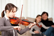 young girl playing violin with her family at home