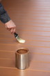 Painter in action, painting floor with brown wood stain