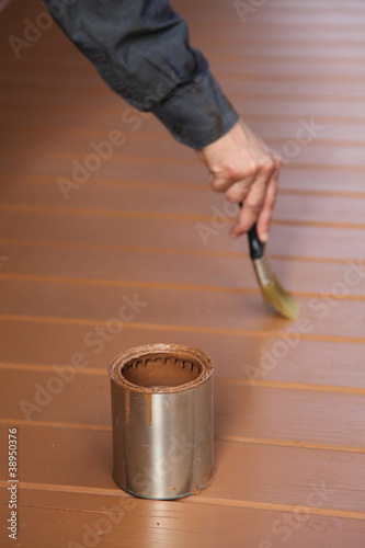 Foto: Painter in action, painting floor with brown wood stain Painter in action, painting floor with brown wood stain