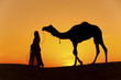 Sunset Silhouette women in a saree walking across the sand dunes