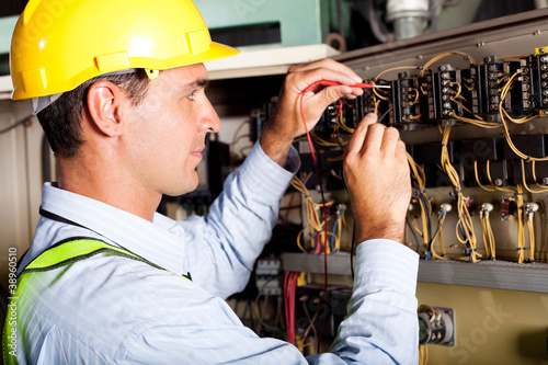 Photo: male electrician testing industrial machine male electrician testing industrial machine