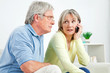 Seniorin telefoniert mit Handy neben Senior