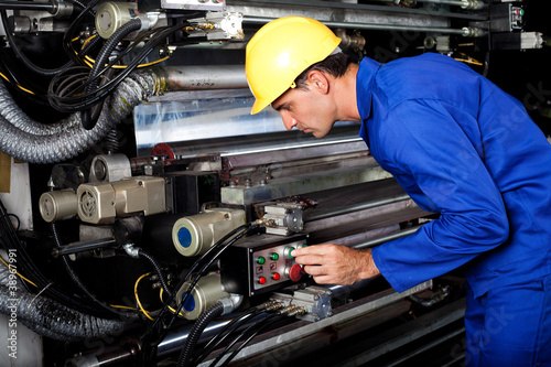 Photo: male printer running modern industrial printing machine male printer running modern industrial printing machine