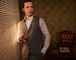 Retro man with a glass standing near window.