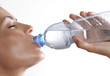 Mujer bebiendo agua mineral de una botella plástica.