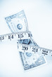 Tape Measure Squeezing Dollar Bill