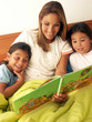 Foto: Madre leyendo un cuento a sus hijas en la cama. Madre leyendo un cuento a sus hijas en la cama.