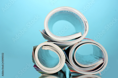 Photo: Rolled up magazines on blue background Rolled up magazines on blue background