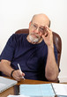 Photo: Senior Man with Checkbook Paying Bills and Worrying Senior Man with Checkbook Paying Bills and Worrying