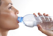 Mujer bebiendo agua mineral de una botella plástica.