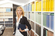 Business Frau steht am Bücherregal