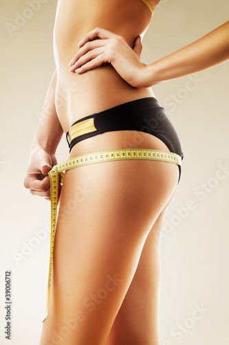Photo: woman body care and yellow measure on thighs woman body care and yellow measure on thighs