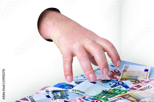 Foto: Hand kommt durch das Loch und nimmt Geld Hand kommt durch das Loch und nimmt Geld