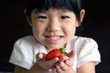Happy little girl hold a strawberry