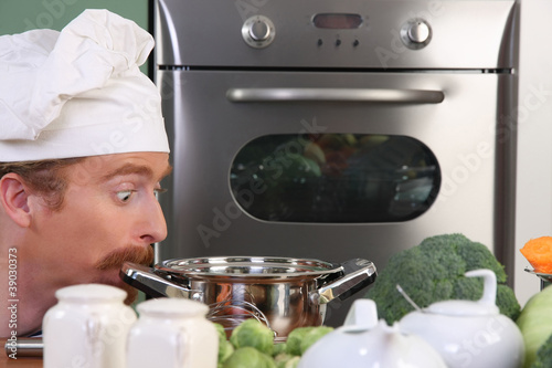 Photo: Funny young chef strange looking at pot Funny young chef strange looking at pot