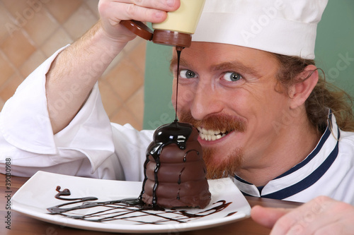 Photo: Funny young chef added chocolate sauce at piece of cake Funny young chef added chocolate sauce at piece of cake