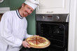 Photo: young chef with italian pizza in kitchen young chef with italian pizza in kitchen