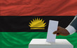 man voting on elections in front of national flag of biafra