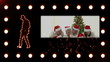 A man dancing with a video showing a family wearing Santa hats