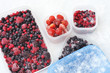 Plastic containers of frozen mixed berries in snow