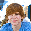 smart boy in puberty sitting on an outdoor table in the village