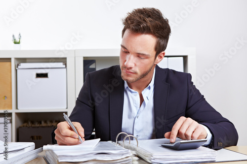 Photo: Mann mit Taschenrechner und Akten Mann mit Taschenrechner und Akten
