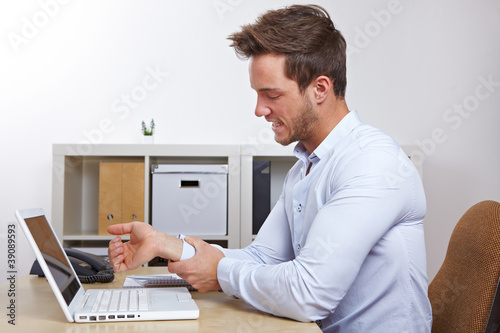 Photo: Mann im Büro mit Sehnenscheidenentzündung Mann im Büro mit Sehnenscheidenentzündung