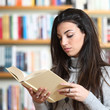 female student reading a book in library