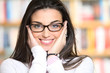 Portrait of beautiful young woman wearing glasses, bookshelf on