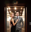 Foto: Retro couple standing against elevator. Retro couple standing against elevator.